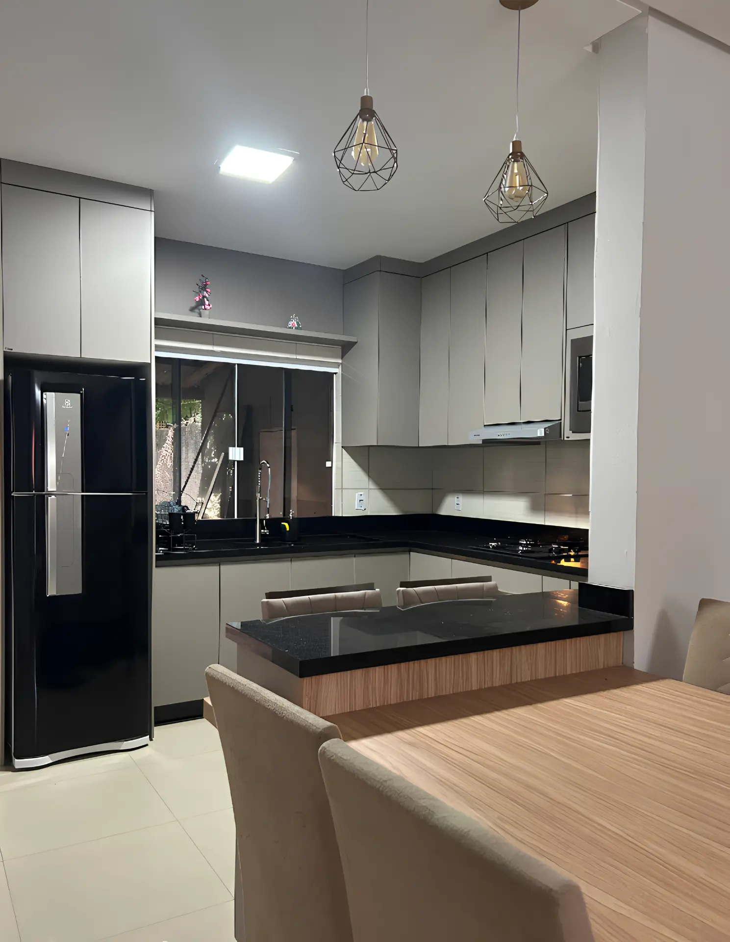 Cozinha integrada com bancada em granito e bancada de refeições