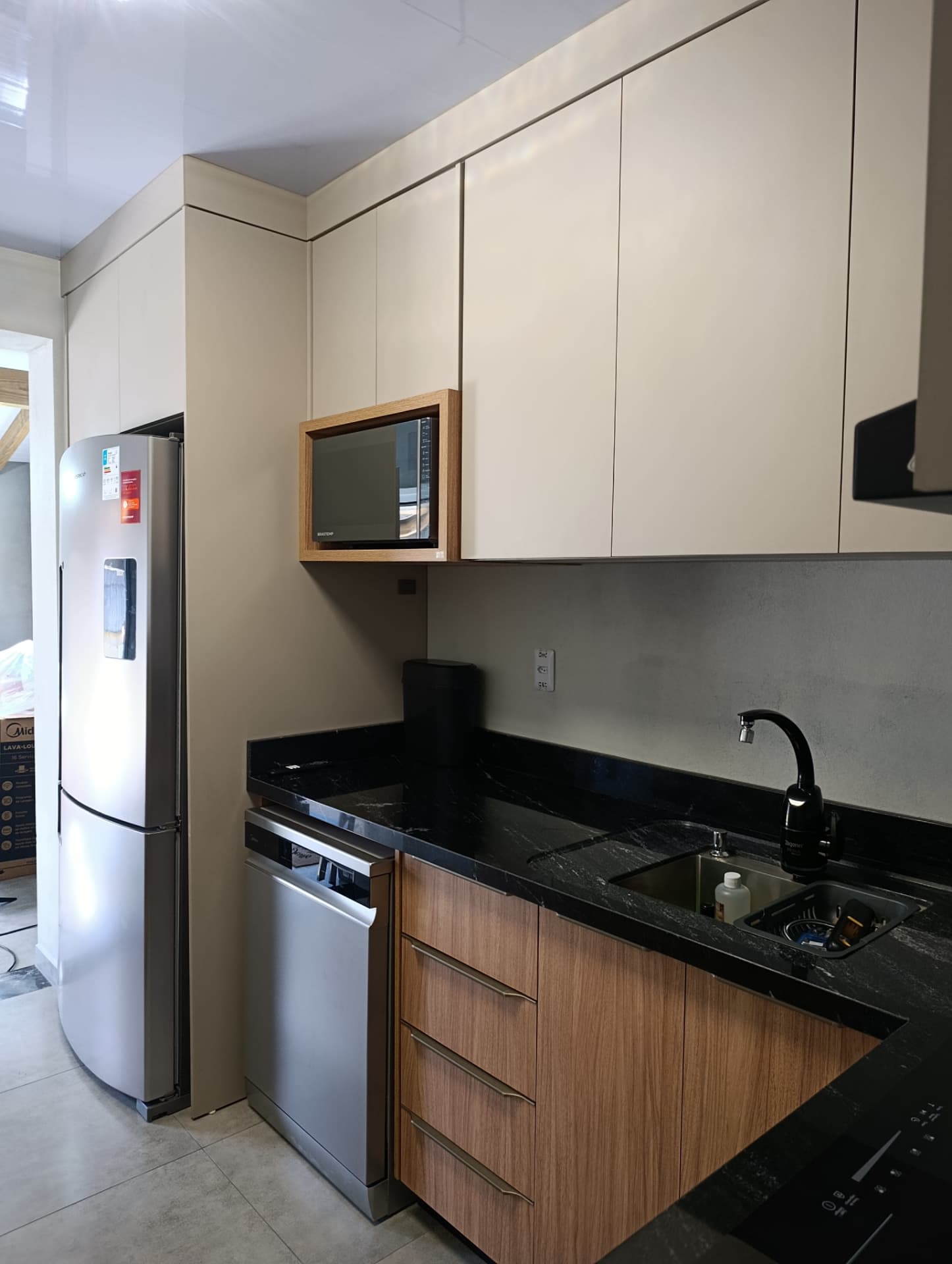 Cozinha planejada com armários claros, madeira e bancada de granito preto